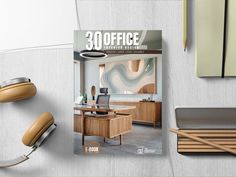 an office desk with headphones on it and a magazine about the interior design process