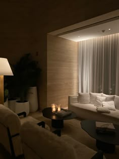 a living room filled with white furniture next to a tall window covered in sheer curtains