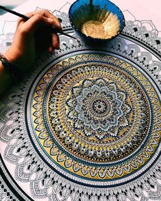 a person is drawing on a large doily with a paintbrush in their hand