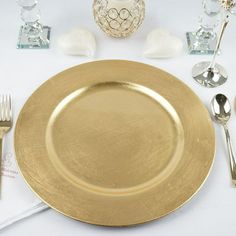 a gold plate with silverware on it and other place setting for a formal dinner