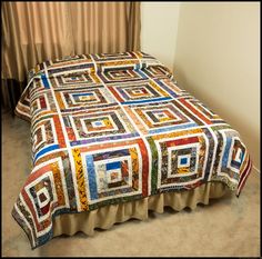 a bed with a multicolored quilt on it's headboard and foot board