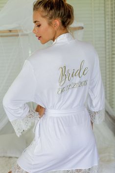 the bride robe is white with gold lettering on it and lace trim around the sleeves