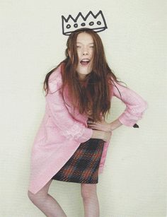 a woman with a crown on her head posing for a photo in front of a white wall