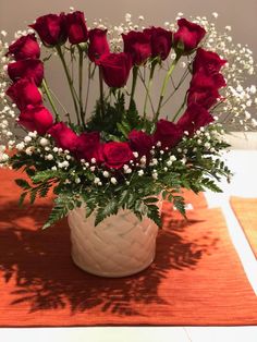 a vase filled with red roses on top of a table