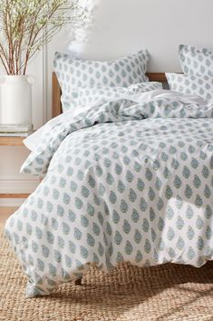 a bed with blue and white bedspread in a room next to a plant