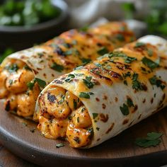 two burritos with chicken and cheese are on a wooden platter next to salad