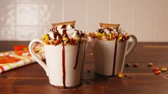 two cups filled with chocolate and marshmallows on top of a wooden table