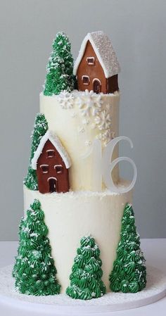 a three tiered cake with trees and houses on the top is decorated in white frosting