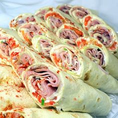 there are many rolls that have meat and vegetables in them on the plate, ready to be eaten