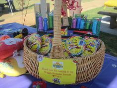 a wicker basket filled with candy sits on top of a blue tablecloth covered picnic table