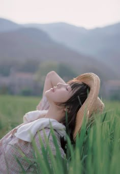 a woman laying in the grass with her eyes closed