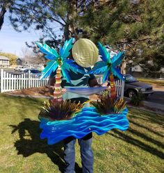 a man standing in the grass holding a blue and green decoration