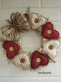 a heart shaped wreath hanging on the side of a wall with buttons and burlocks