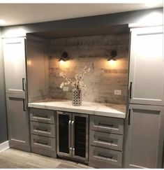 an empty kitchen with gray cabinets and white counter tops in the center is a vase with flowers on it