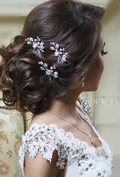 a woman in a wedding dress with hair combs on her head and flowers in her hair