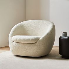 a white chair sitting on top of a wooden floor next to a black trash can