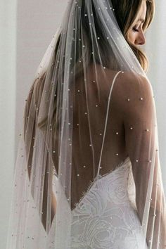 a woman in a wedding dress wearing a veil with pearls on the back of her head