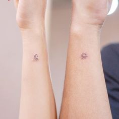 two people with matching wrist tattoos on their arms, one has a sun and the other is a moon