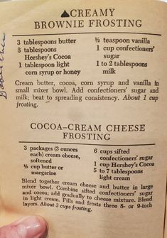 a hand holding an old recipe book in it's left side, with instructions on how to make chocolate cream cheese frosting