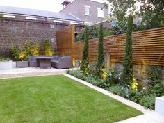 an outdoor garden with grass and plants on the side of the fenced in area