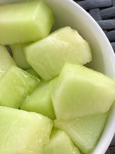 a white bowl filled with cut up pieces of cucumber sitting on top of a table