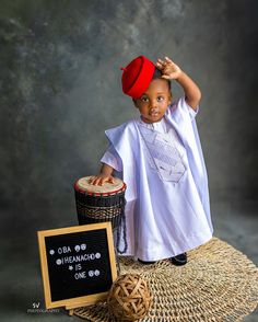 a little boy sitting on top of a table next to a basket and a sign