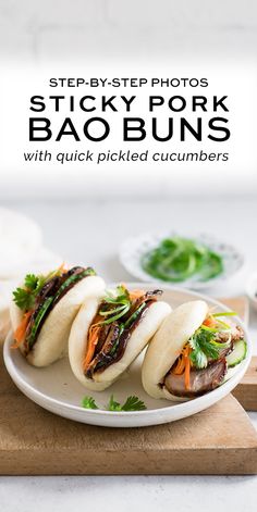 three pork bao buns with pickled cucumbers on a white platter