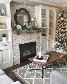 a living room filled with furniture and a christmas tree in front of a fire place