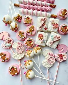 a table topped with lots of pink and white candy covered lollipops next to marshmallows