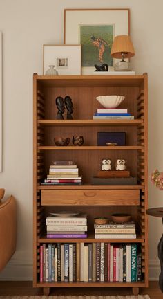 a bookshelf filled with lots of books next to a lamp and vase on top of a table