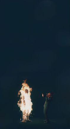 two people standing in the dark with fire coming out of their mouths and hands behind them