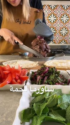 a woman cutting up food on top of a counter next to other foods and vegetables