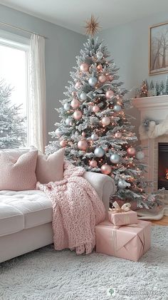 a christmas tree with pink and silver ornaments in a living room next to a white couch