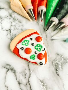 a cookie shaped like a slice of pizza surrounded by crayons