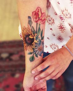 a woman's arm with sunflowers and roses on it