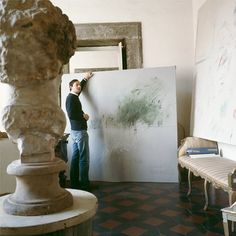 a man standing next to a white board in a room with paintings on the wall