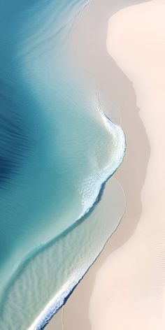 an aerial view of the ocean and beach from above, with white sand in the foreground