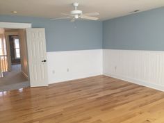 an empty room with hard wood floors and white trim on the walls is painted blue