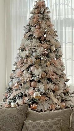 a decorated christmas tree sitting on top of a couch in front of a white window