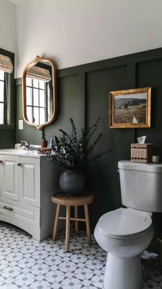 a white toilet sitting next to a bathroom sink under a mirror on top of a wall