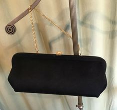 "This is a vintage, black purse, from the 50s or 60s. No labels or names inside. The purse has a single center compartment. The purse is made of black fabric. The hardware & optional chain handles are gold tone metal & it closes with a push clasp with a rhinestone centerpiece. The bag measures 5.5\" tall, 1-1/2\" across the bottom, and 12\" wide. Handle drop measures 5.5\". Inside is lined with fabric & the handle can be tucked inside for use as a clutch. It is in good, vintage condi Classic Rectangular Evening Bag For Vintage Events, Vintage Black Rectangular Evening Bag, Retro Black Evening Bag For Formal Occasions, Vintage Black Clutch For Evening, Vintage Black Evening Clutch, Elegant Vintage Black Bag For Formal Occasions, Elegant Vintage Black Formal Bag, Elegant Rectangular Evening Bag For Luncheon, Vintage Evening Bag With Chain Strap For Formal Occasions