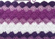 a crocheted purple and white blanket with the word love written in pink on it