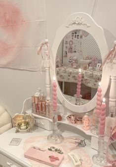 a white vanity with pink accessories on it and a large mirror above the table in front of it