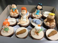 there are many cupcakes in the box with fondant figures on them,