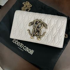 Roberto Cavalli Mirror Snake Shoulder Bag Brand New. Never Worn! Dust Bag Included. Retail Price: $1050 Color: Tan The Mirror Snake Is A Cavalli Signature And It Adorns The Front Of This Shoulder Bag In The Form Of A Silver-Tone Metal Plaque. The Compact Design Is Crafted From Blue Grained Leather And Suspends From A Chain Strap. Mirror Snake Shoulder Bag Detachable Chain Shoulder Strap Two Internal Compartments Internal Slip Pocket Front Flap With Press-Stud Fastening 100% Leather Made In Italy Luxury Beige Clutch Shoulder Bag, Luxury Cream Shoulder Bag, Luxury Beige Clutch Bag, Luxury Cream Shoulder Bag For Party, High-end Cream Evening Bag, Luxury Cream Shoulder Bag For Evening, Designer Cream Shoulder Bag For Evening, Robert Cavalli, Snake Bag