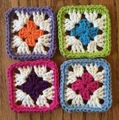 four square crocheted coasters sitting on top of a wooden table