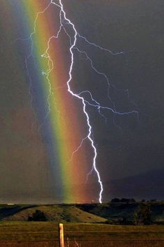 a rainbow is seen in the sky with lightning