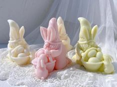 three different colored soaps sitting on top of a white lace covered tablecloth,