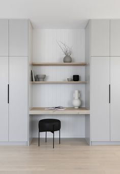 an empty room with shelves, chairs and a vase on the table in front of it