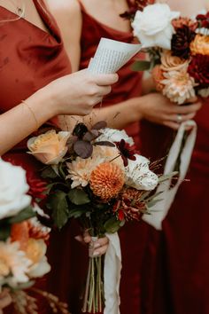 the bridesmaids are holding their bouquets with paper in each other's hands